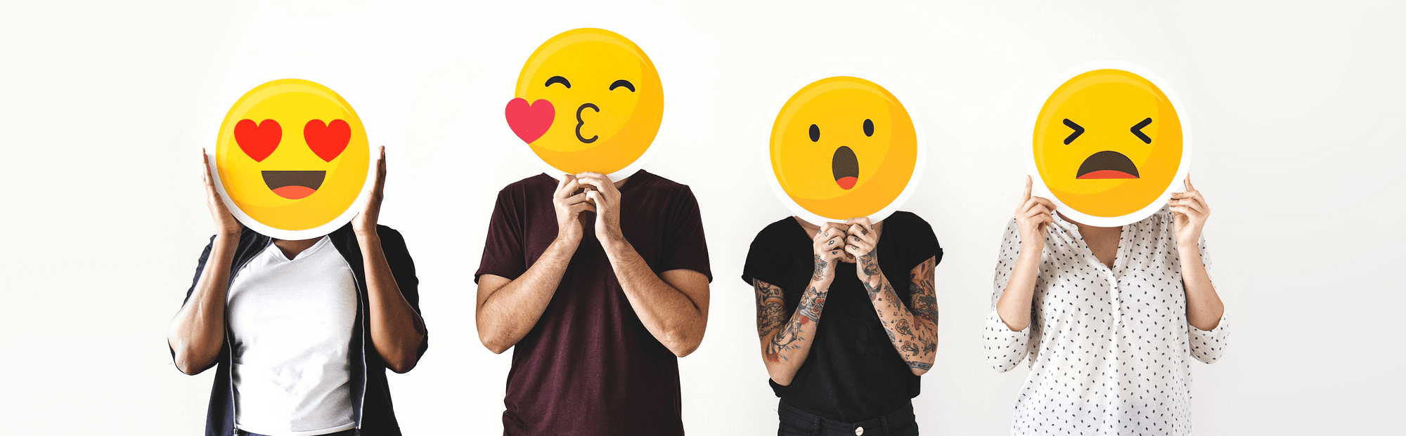 Quatro pessoas seguram emojis amarelos diante do rosto: apaixonado, beijo, surpreso e irritado