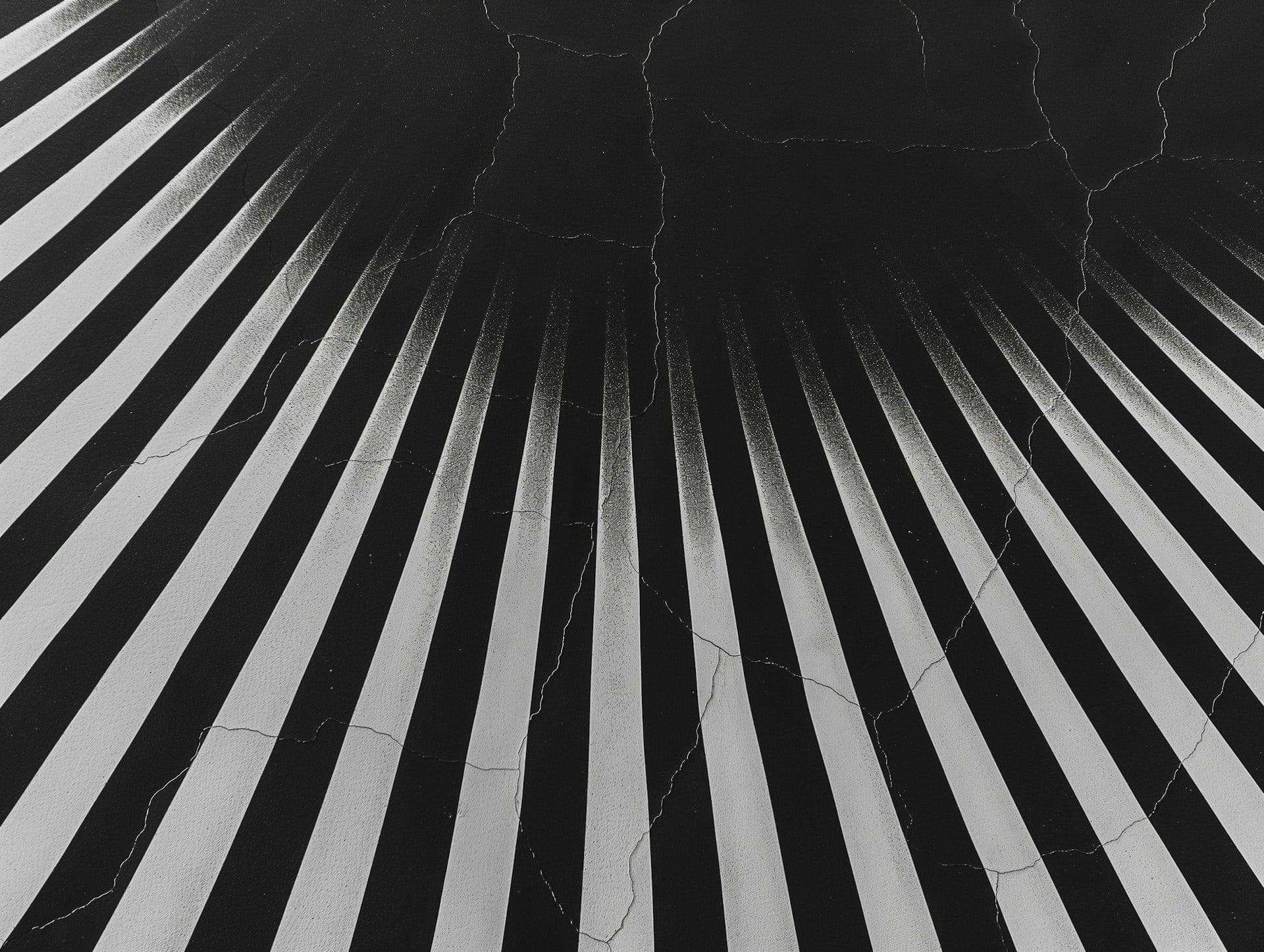 Faixas brancas e pretas em perspectiva, partindo de um ponto no alto sobre uma superfície preta rachada
